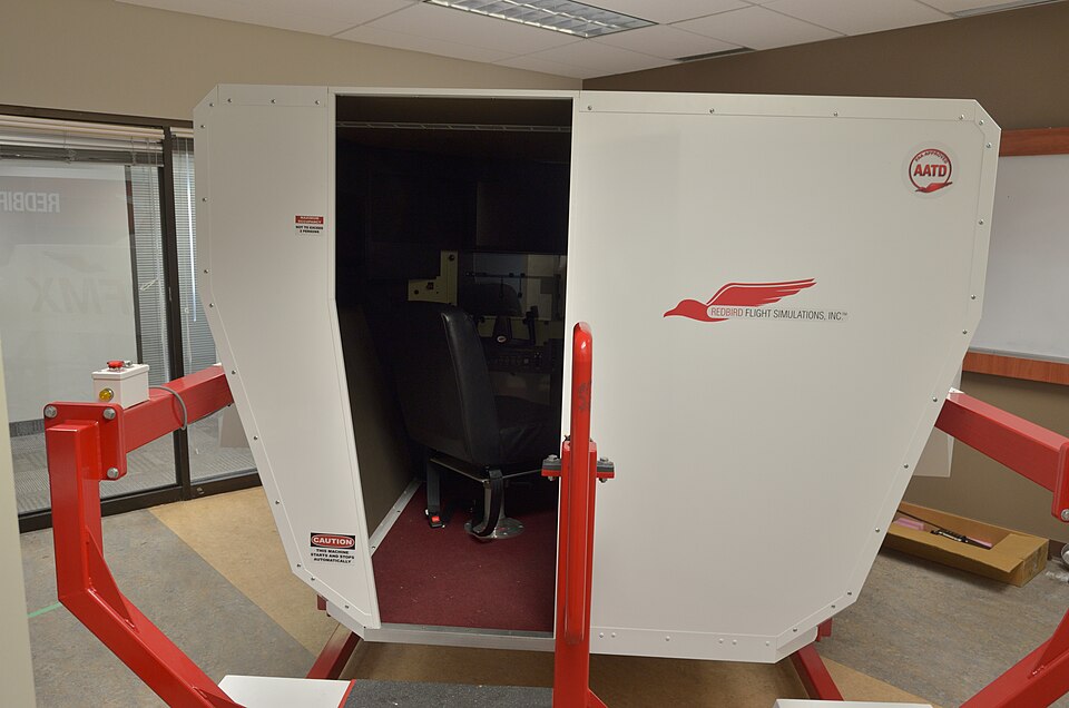 An enclosed Redbird flight simulator with its entrance open.