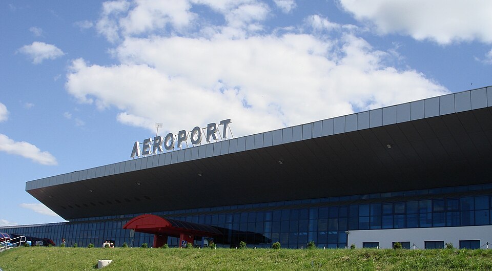 Low airport terminal with a broad roof canopy, glazed façade and AEROPORT lettering.