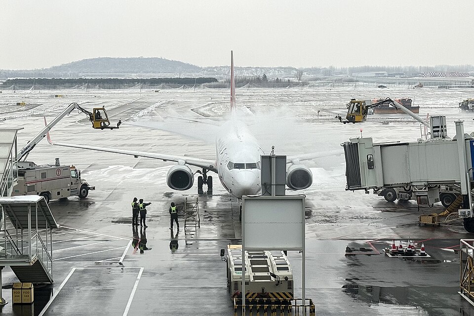 Airliner facing the camera at a snowy gate with raised service platforms on both sides.