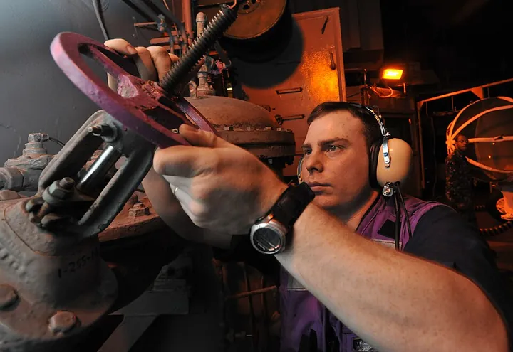 A technician operates a fuel valve for an engine test.
