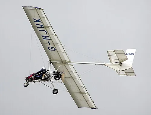 An open-frame ultralight aircraft flying above the camera.