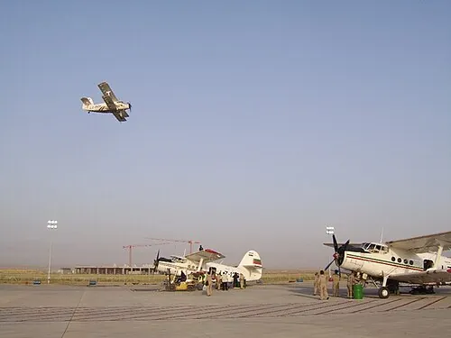 Agricultural An-2 biplanes on an airfield, with one aircraft above them.