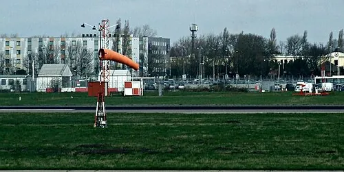 Orange windsock beside pavement at Heathrow Airport.