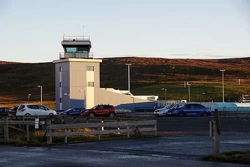 Control tower building at Scatsta Airport beneath low hills.