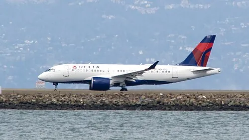 A Delta Airbus A220 accelerating along a runway.