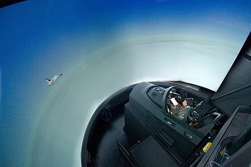 A person using a T-45C flight simulator surrounded by a projected view.
