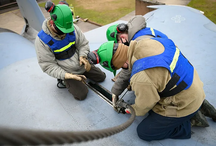 A team attaches a lifting sling during an aircraft-recovery exercise.