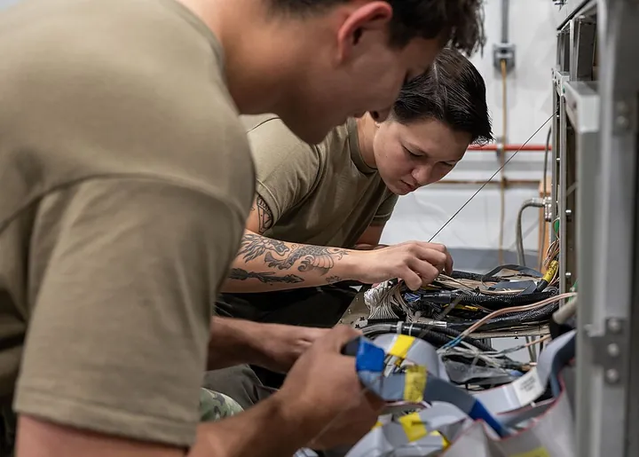 Technicians examine cables and wiring used in aircraft avionics.