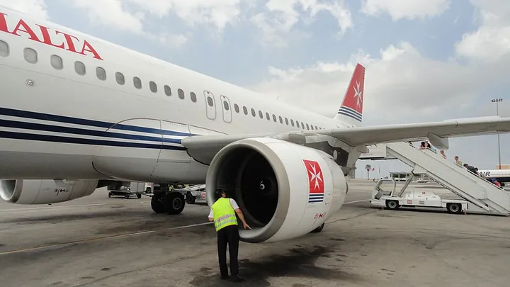 An Air Malta crew member performing a pre-flight inspection of an Airbus A320.
