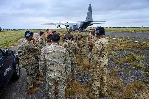 A group gathered for a briefing beside an aircraft.