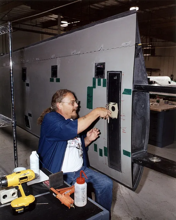 A technician fits a drilling template during construction of a composite aircraft wing.