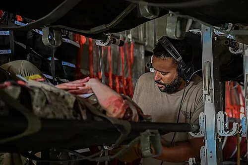 Personnel securing a simulated patient inside a military transport aircraft.