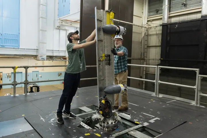 Technicians install pieces of a wing model before a wind-tunnel test.