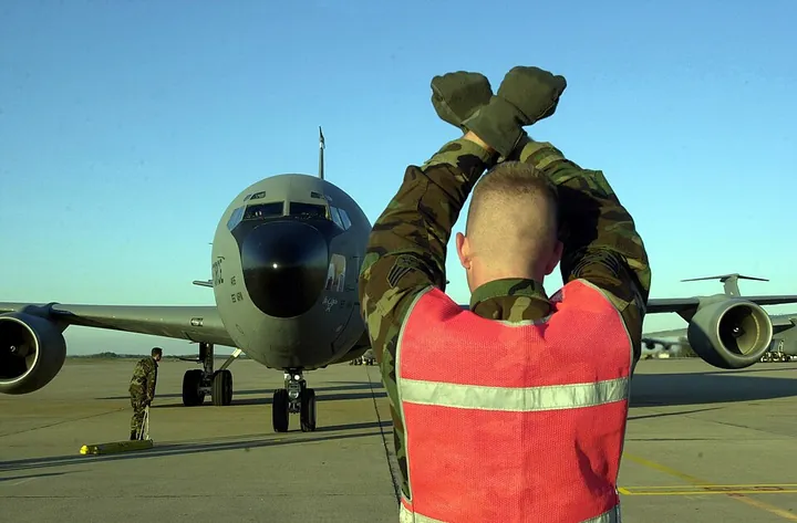A marshaller directing a KC-135R on a flight line