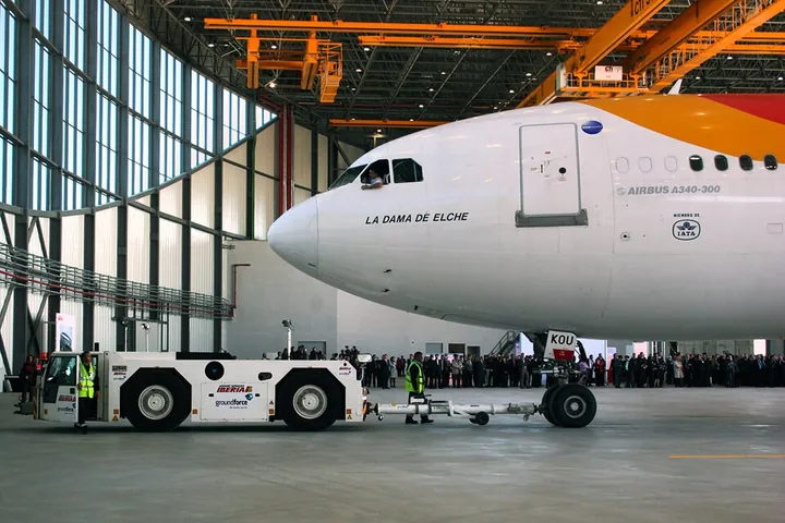 An airliner's nose enters a maintenance hangar.