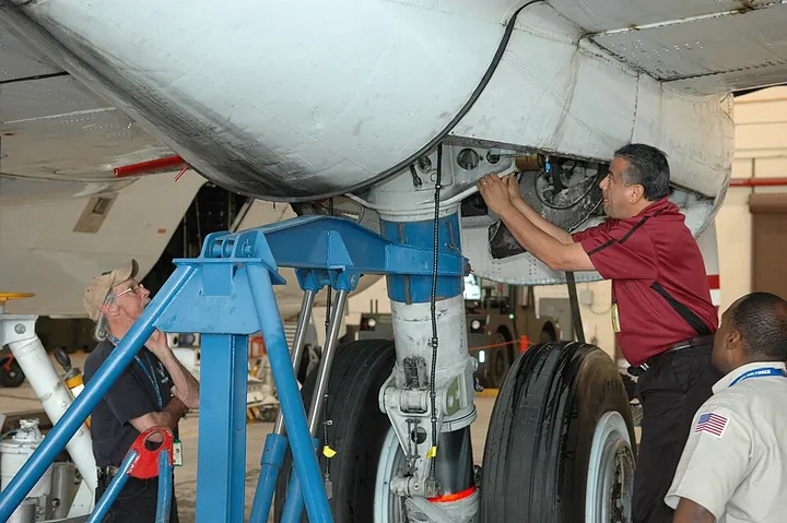 Technicians inspect a Super Guppy's main landing gear.