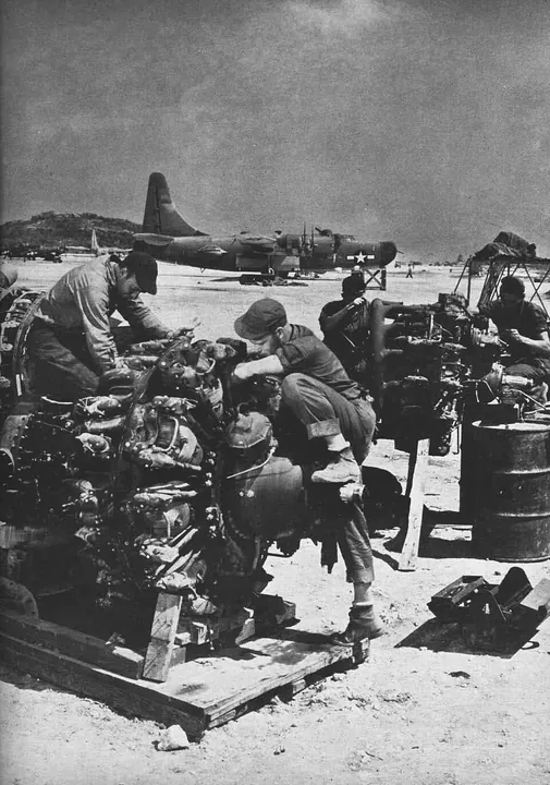 Maintenance personnel work on aircraft engines outdoors on Okinawa in 1945.