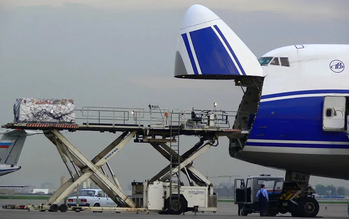 A Boeing 747 freighter with its nose cargo door open beside a loader at Sheremetyevo Airport