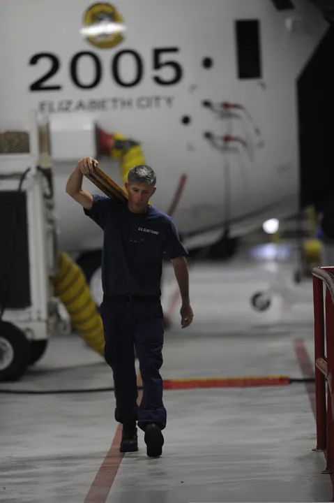 A technician carries tools to a propeller-maintenance task.