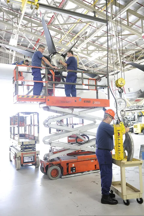Coast Guard technicians work together on an aircraft propeller.