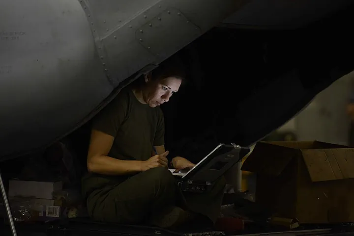 An avionics technician consults a computer-based maintenance manual.
