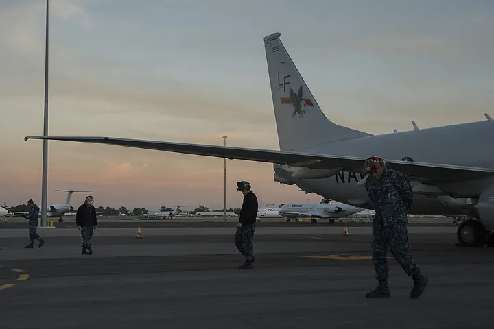 Personnel checking for foreign-object debris around a P-8A at Perth Airport