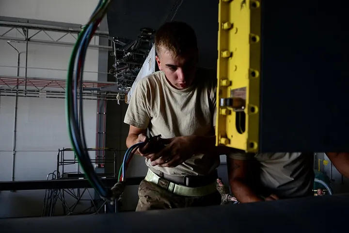 A technician performs electrical maintenance on an EC-130H.