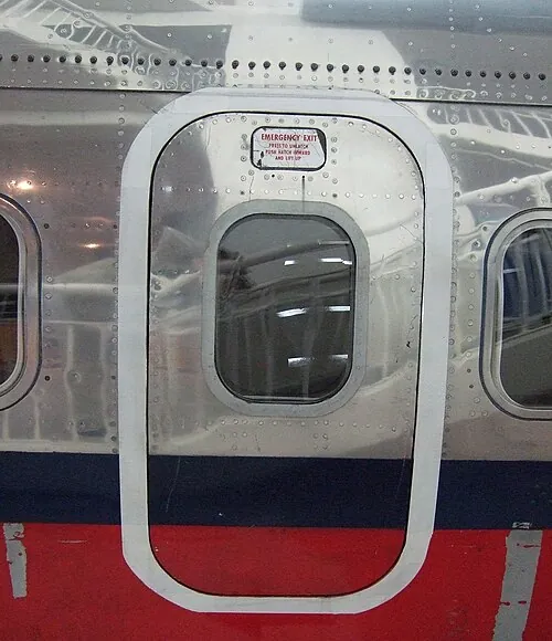A detached Boeing 737 overwing exit door displayed beside an aircraft fuselage.