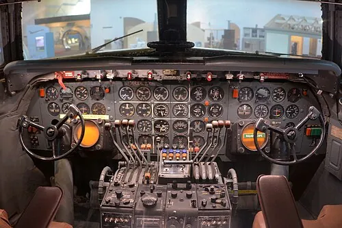 Preserved Douglas DC-7 cockpit with round instruments and control wheels.