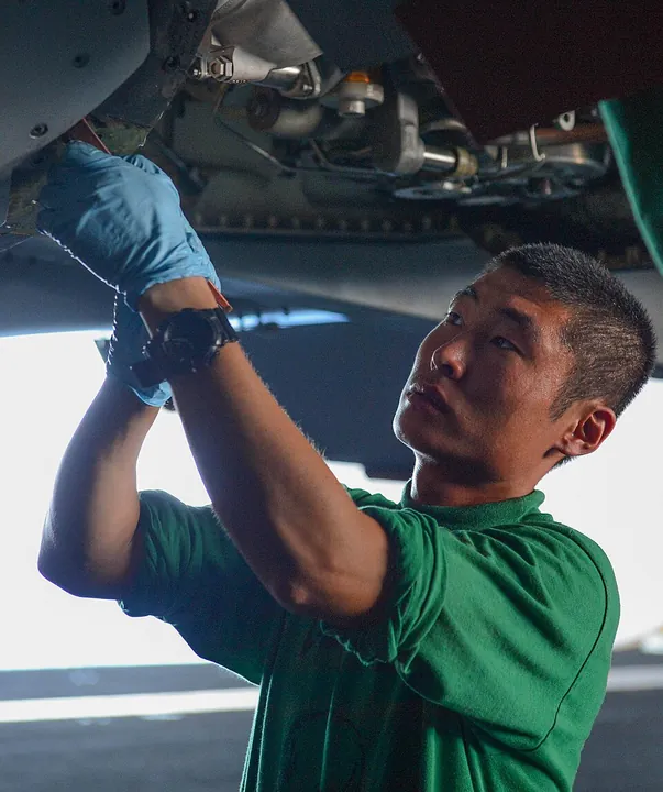 A technician performs corrosion maintenance on an aircraft.