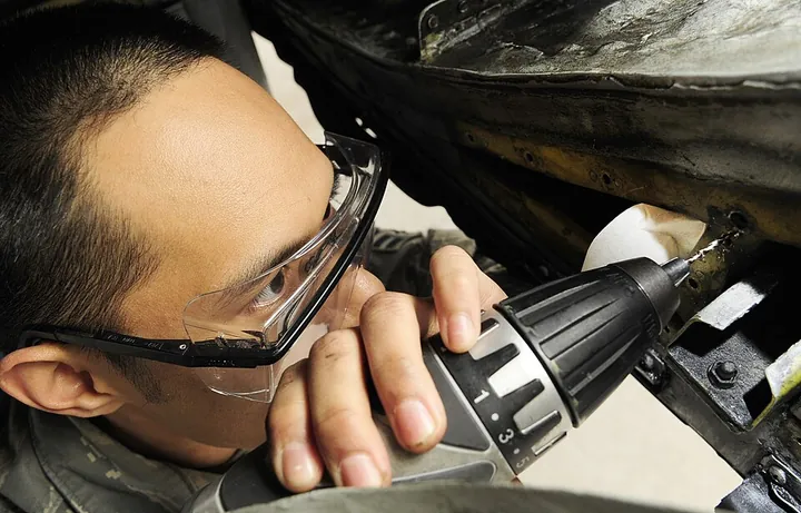 A technician removes a nut plate from an aircraft.