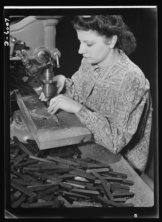 A factory worker uses a boring machine during a wartime transition from piano work to aircraft-engine parts.