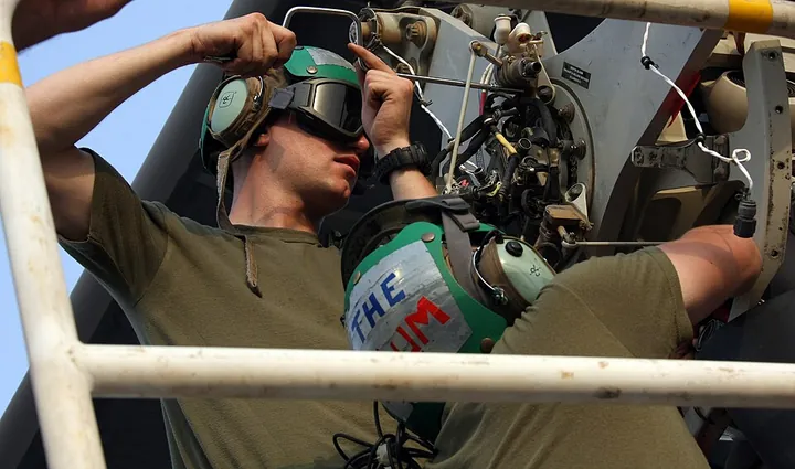 A technician works to remove the rotor head from an MV-22.