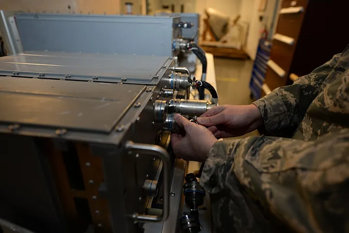 A technician connects an electrical plug to a radar signal-processing unit.