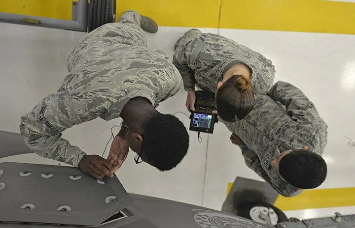 Technicians check an aircraft panel using ultrasonic equipment.