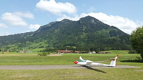 A white sailplane beginning its launch on an airfield.