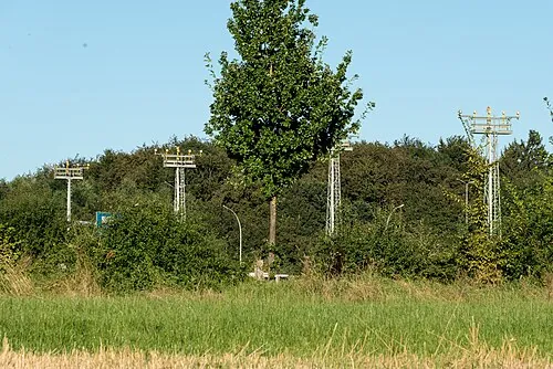 Approach-light supports among grass and trees near Luxembourg Airport.