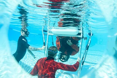 A training seat and participants in a pool-based escape exercise.
