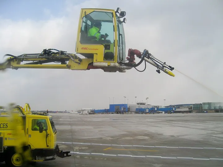 An operator in the enclosed working basket of an airport deicing truck