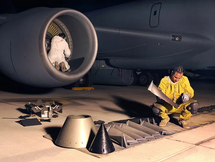A technician visually inspects blades removed from an engine fan assembly.