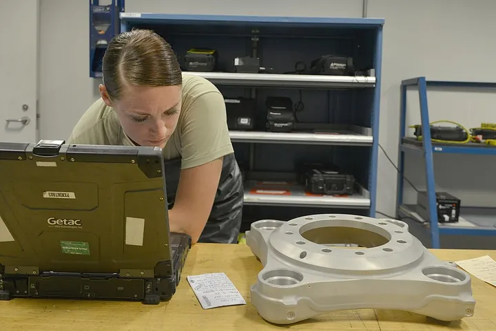 An inspection technician consults digital technical instructions for a brake component.