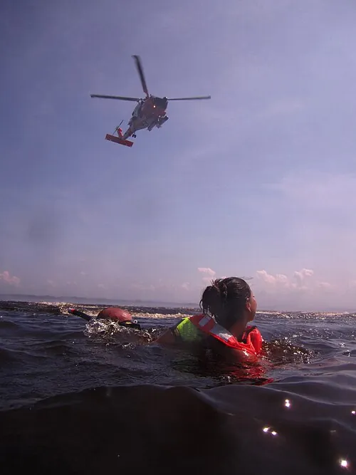 People in the water beneath a hovering rescue helicopter.