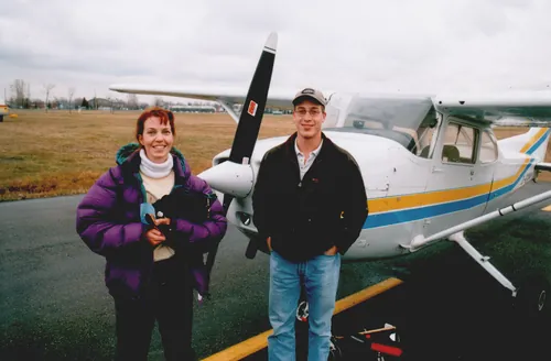 Two people standing beside a Cessna 172 light aircraft.
