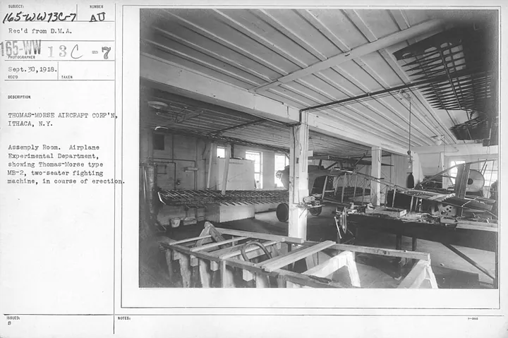 An aircraft factory assembly room shows early production work.