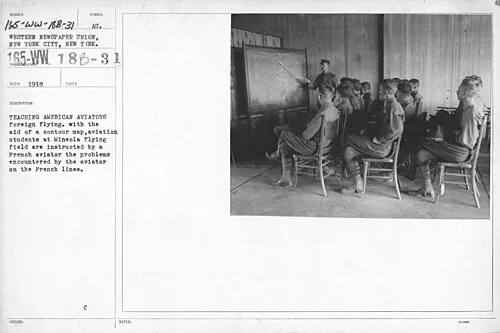 An archival photographic record showing aviation pupils seated in a classroom, with a map on the wall.