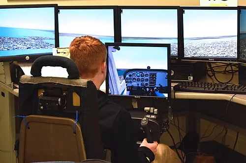 A learner seated at a flight simulator with instrument displays.