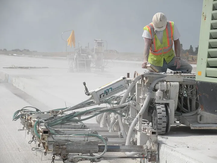 A construction worker operating a dowel-drilling machine on a runway