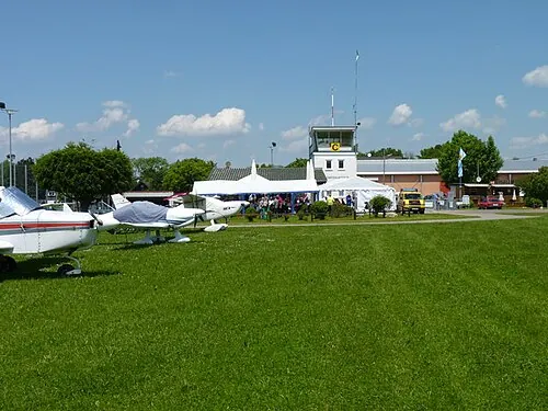 Small aerodrome control building with light aircraft parked on the grass.