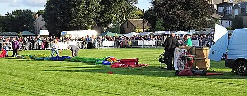 People setting up a hot-air balloon on a field.