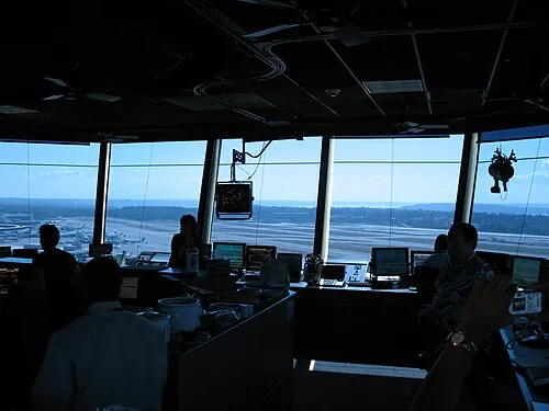 Darkened Seattle-Tacoma control-tower interior with runways visible through wide windows.
